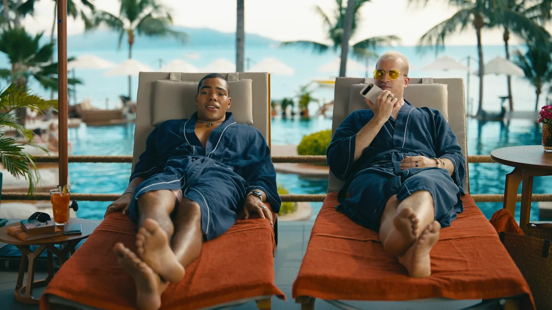 Two people relaxing beside a bright blue pool.